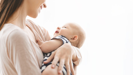 Smiling young woman lulling her newborn child in arms