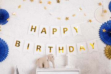 Birthday decorations with gifts, toys, balloons, garland and figure 1 for little baby party on a white wall background.