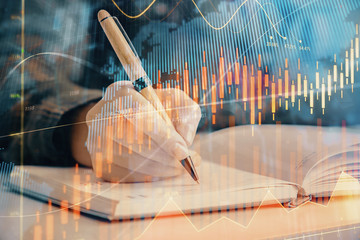 Multi exposure of woman's hands making notes with forex graph hologram. Concept of technical analysis.