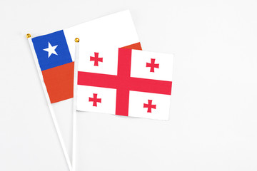 Georgia and Chile stick flags on white background. High quality fabric, miniature national flag. Peaceful global concept.White floor for copy space.