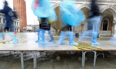 people on the footbridge with plastic gaiters in Venice in Italy