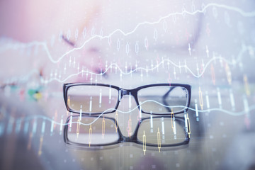 Hand taking notes in notepad. Forex chart holograms in front. Concept of research. Double exposure