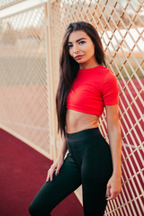 Beautiful fitness woman in sportswear posing near grid.