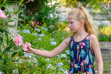 Beautiful little blonde girl with long hair, teenager, in the garden, summer