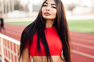 Beautiful fitness woman in sportswear posing near running track.