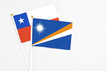 Marshall Islands and Chile stick flags on white background. High quality fabric, miniature national flag. Peaceful global concept.White floor for copy space.