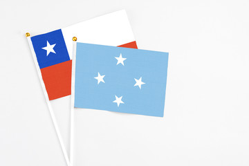 Micronesia and Chile stick flags on white background. High quality fabric, miniature national flag. Peaceful global concept.White floor for copy space.