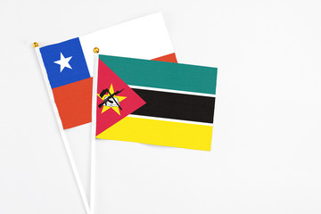Mozambique and Chile stick flags on white background. High quality fabric, miniature national flag. Peaceful global concept.White floor for copy space.