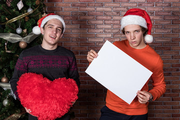 Two funny young men celebrating christmas over brick wall