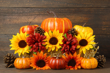 Fall decoration of Sunflowers, Mum flowers pumpkins and gourds arranged on bale of hay, Thanksgiving still life with rustic wooden background, fall background