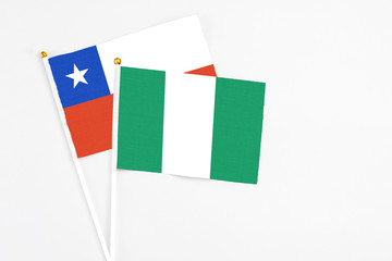 Nigeria and Chile stick flags on white background. High quality fabric, miniature national flag. Peaceful global concept.White floor for copy space.