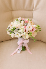 Very beautiful classic Bridal bouquet with roses, freesia, eustoma on beige background