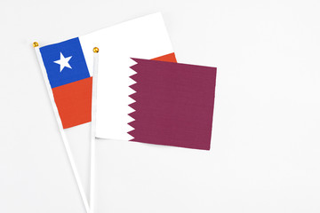 Qatar and Chile stick flags on white background. High quality fabric, miniature national flag. Peaceful global concept.White floor for copy space.