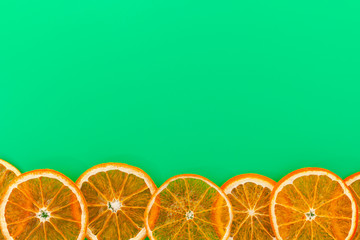 Christmas greeting card. Slices of dried oranges at the bottom on a green background. Top view, copy space.