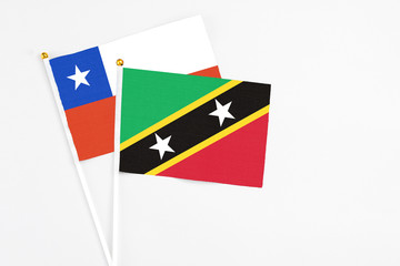 Saint Kitts And Nevis and Chile stick flags on white background. High quality fabric, miniature national flag. Peaceful global concept.White floor for copy space.