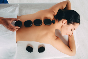 Hot stone treatment at spa resort. Woman while hot stone massage, view from above