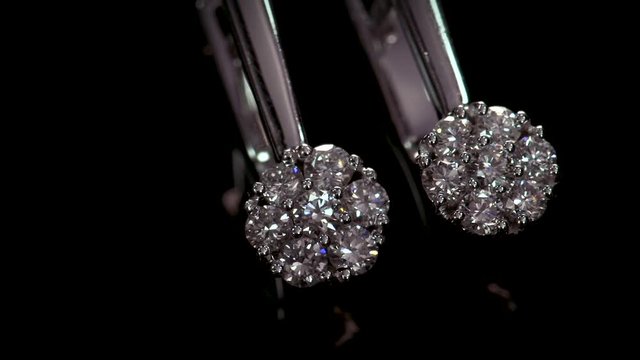 White gold earrings with shining diamonds on black background. Luxury jewelry
