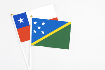 Solomon Islands and Chile stick flags on white background. High quality fabric, miniature national flag. Peaceful global concept.White floor for copy space.