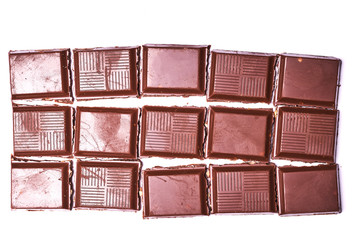 Chocolate bar broken into pieces and isolated on white background