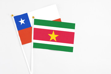 Obraz premium Suriname and Chile stick flags on white background. High quality fabric, miniature national flag. Peaceful global concept.White floor for copy space.