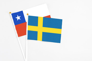 Sweden and Chile stick flags on white background. High quality fabric, miniature national flag. Peaceful global concept.White floor for copy space.