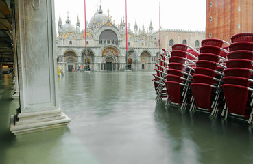Red chairs in Saint Mark Square in Venice during awesome high ti