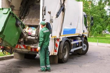 Garbage collection worker operating garbage compressor track in residential area.