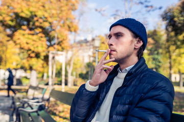 Young man on a bench with a cigarette