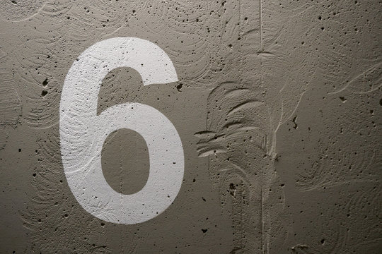 The number 6 painted stencil on a concrete wall