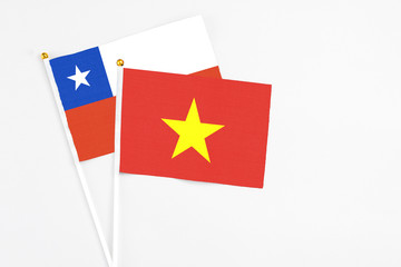 Vietnam and Chile stick flags on white background. High quality fabric, miniature national flag. Peaceful global concept.White floor for copy space.