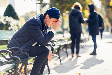 Obraz premium Worried young man on a bench during autumn day
