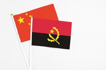 Angola and China stick flags on white background. High quality fabric, miniature national flag. Peaceful global concept.White floor for copy space.
