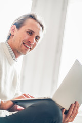 Young man looking at his portable computer. Bright light in the background.