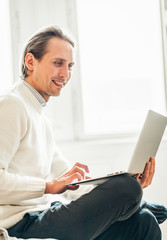 Young man looking at his portable computer. Bright light in the background.