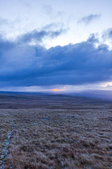 A view of a majestic sunrise in the mountain with orange circular bright sun and some grey clouds