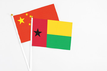 Guinea Bissau and China stick flags on white background. High quality fabric, miniature national flag. Peaceful global concept.White floor for copy space.