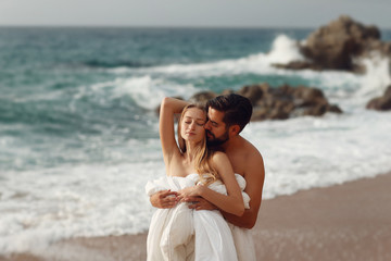 Fototapeta na wymiar Young beautiful couple on beach in blankets