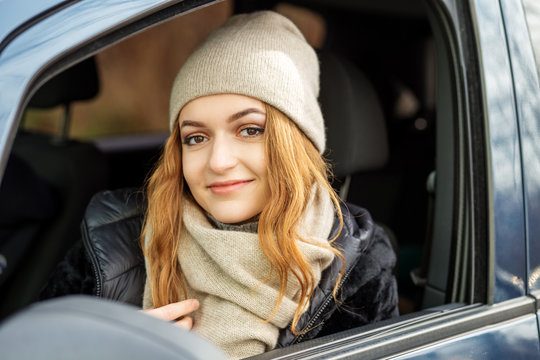 Young woman driving a car. Beige hat and scarf. Concept lifestyle, autumn, auto driver.