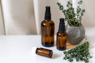 Close up photo of glass bottles of essential oils and freshherbs on white drapery background. Aromatherapy concept photo, horizontal orientation.