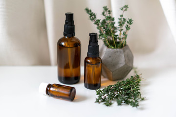 Close up photo of glass bottles of essential oils and freshherbs on white drapery background. Natural pharmacy concept photo, horizontal orientation.