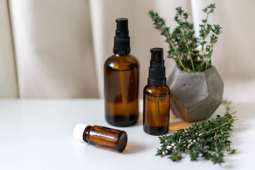Glass bottles of essential oils and fresh thyme on white drapery background. Natural pharmacy concept photo, horizontal orientation.