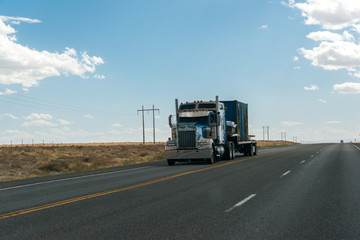 Fototapeta na wymiar A truck crosses the desert lands of Utah under a blue and cloudy sky