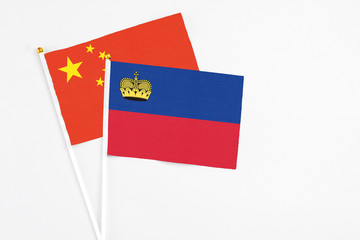 Liechtenstein and China stick flags on white background. High quality fabric, miniature national flag. Peaceful global concept.White floor for copy space.