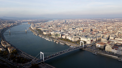 The highest point of Budapest with a view of the city panorama. A river with bridges and ships. Sunset sun. Chain bridge, palace and parliament. Top view.