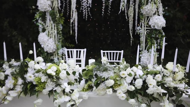Amazing banquet wedding table decorated with an arch and white bouquets of natural flowers of roses and eustoma