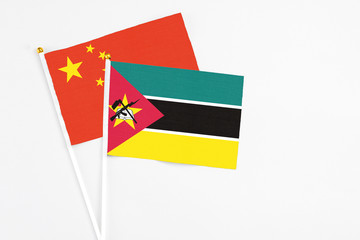 Mozambique and China stick flags on white background. High quality fabric, miniature national flag. Peaceful global concept.White floor for copy space.