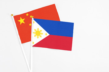 Philippines and China stick flags on white background. High quality fabric, miniature national flag. Peaceful global concept.White floor for copy space.