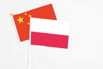 Poland and China stick flags on white background. High quality fabric, miniature national flag. Peaceful global concept.White floor for copy space.