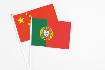 Portugal and China stick flags on white background. High quality fabric, miniature national flag. Peaceful global concept.White floor for copy space.