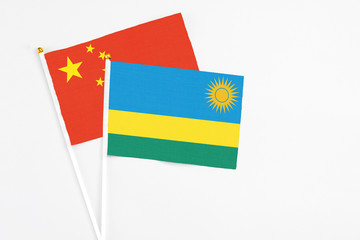 Rwanda and China stick flags on white background. High quality fabric, miniature national flag. Peaceful global concept.White floor for copy space.